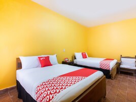 Habitación de hotel con dos camas, cada una con ropa de cama blanca y detalles en rojo, y un cabecero de madera.