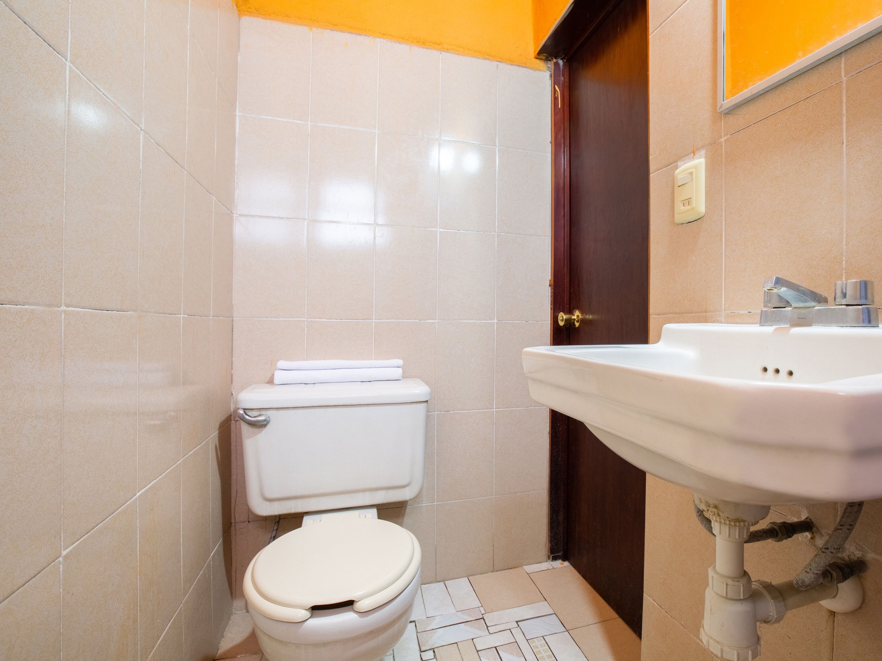 Un bagno piccolo con il water, lavandino e pareti piastrellate.