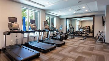 A gym with treadmills, exercise bikes, and a mirrored wall.