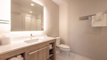 A modern bathroom with a large mirror, a sink, a toilet, and a towel rack.