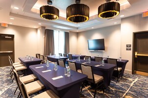A conference room with tables, chairs, water bottles, and a TV screen.