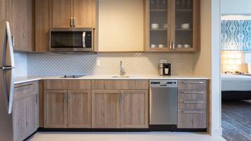 Une cuisine moderne avec des meubles en bois, un four à micro-ondes encastré, un lave-vaisselle et une machine à café.