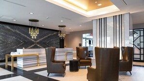 Un vestíbulo moderno con una mesa de recepción, sillones de cuero y una pared de mármol.
