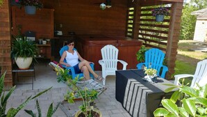 A covered outdoor seating area with a wooden pergola, a table with a plant, and several chairs.