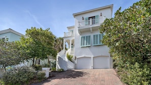 A two-story white building with a balcony, a driveway, and surrounding greenery. - January Beach Bliss for 2 OR 4!  Beach, Sunsets, pool, tennis!  US Senic 98 (Destin)