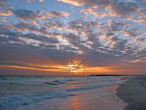 Een strand met golven en een zonsondergang.