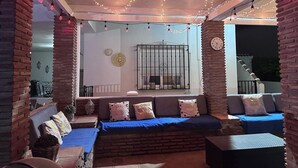 Un espace extérieur aménagé avec des murs en briques, des guirlandes lumineuses et une horloge.