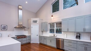 Una cocina moderna con gabinetes grises, estufa de acero inoxidable y lavavajillas.