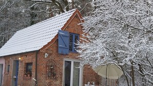 Ett hus byggt av tegel med ett snötäckt tak och en skjutdörr av glas.