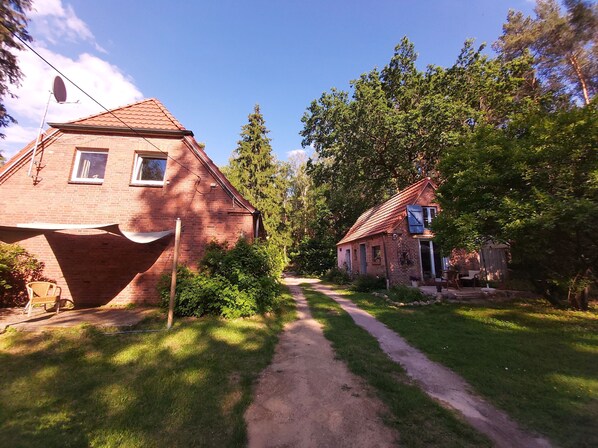 A brick house with a sloped roof, a small porch, and a pathway leading to a wooden door. - Modernized stable with comfort and flair between forest and lake (Dobbertin)