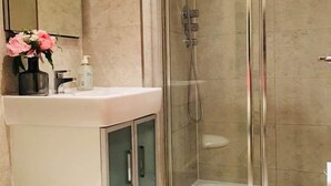 Une salle de bain moderne avec une douche à parois de verre, un lavabo blanc avec un miroir au-dessus et des toilettes.