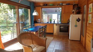 Une cuisine équipée d’une table à manger, de chaises, d’un réfrigérateur et offrant une vue sur l’extérieur.