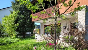 Une propriété résidentielle dotée d’un jardin, d’un espace extérieur aménagé et d’une façade en briques.