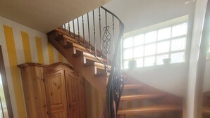 Un escalier en bois avec une rampe en métal, un meuble en bois et une fenêtre donnant sur l’extérieur.