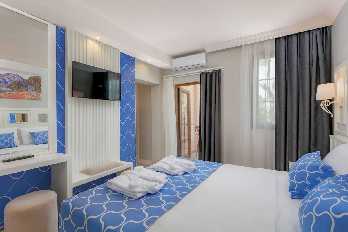 A hotel room with a bed, a TV, a desk, and a bathroom visible through an open door.