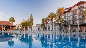 Ein Hotel mit Pool, Palmen und einem Mehrstöckiger Gebäude mit Balkonen.