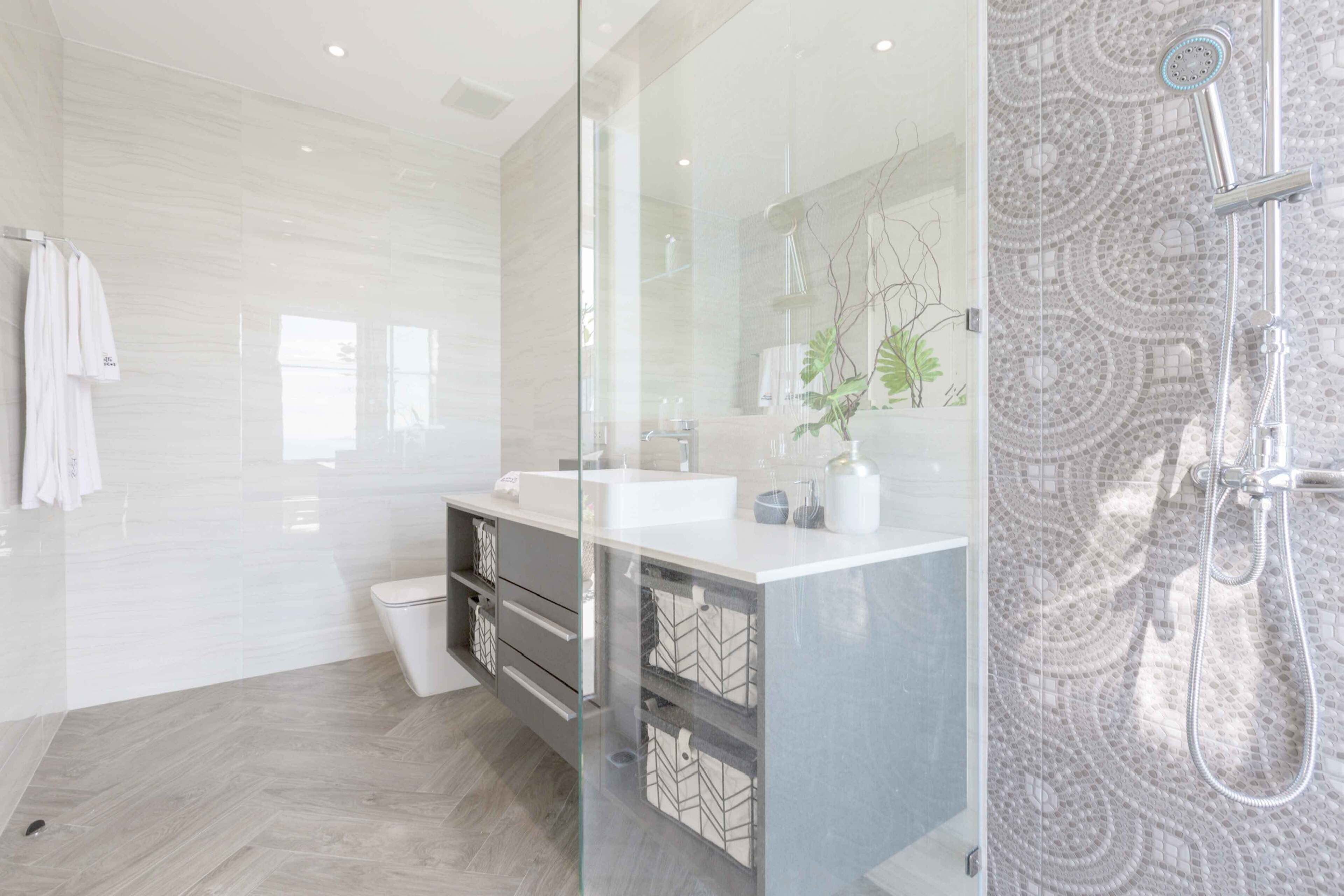 Une salle de bain moderne avec une douche à parois de verre, un lavabo blanc et un grand miroir.