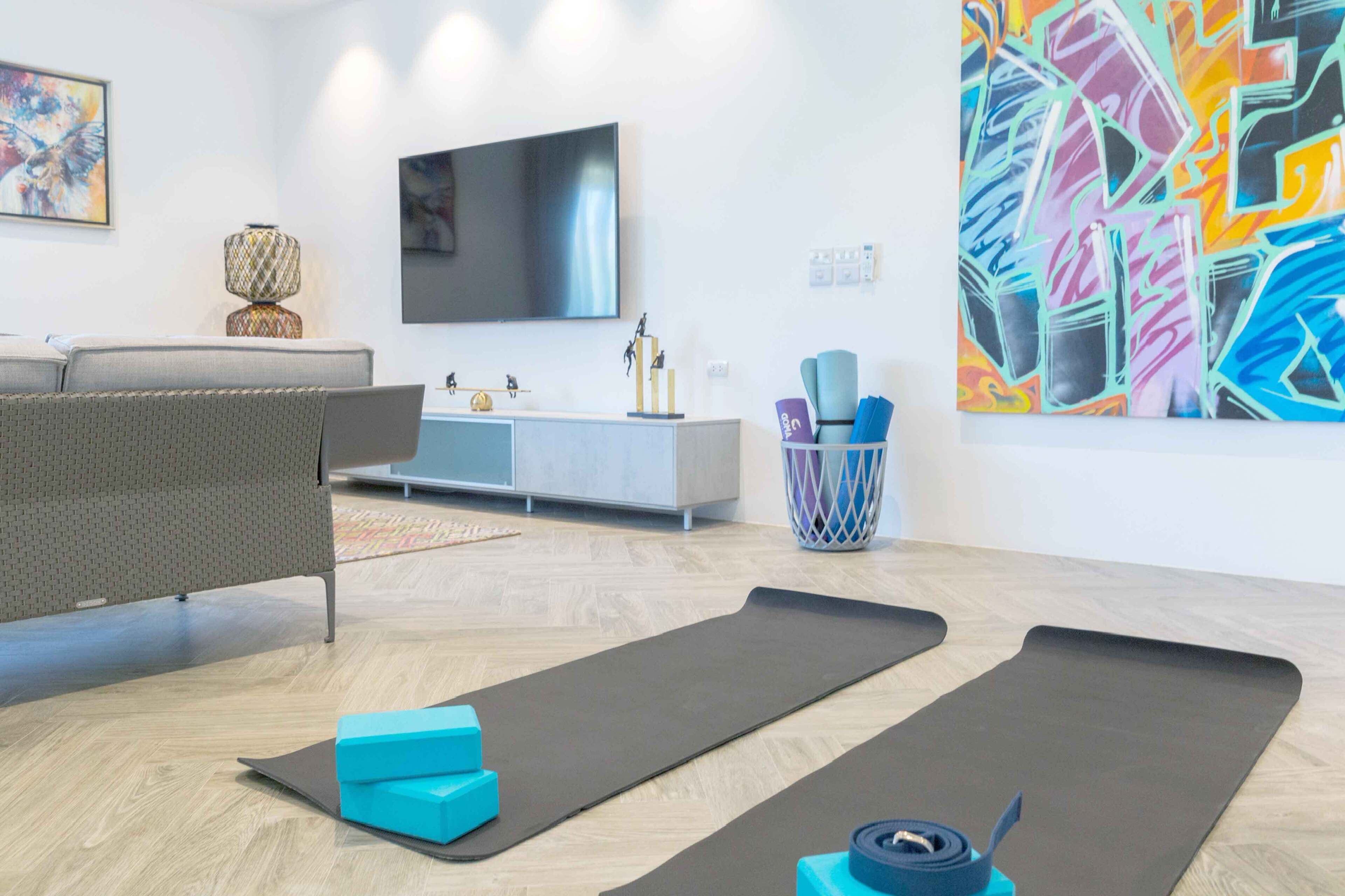 A modern living room with a grey sofa, a flat-screen TV, a grey cabinet, and a colorful abstract painting on the wall.