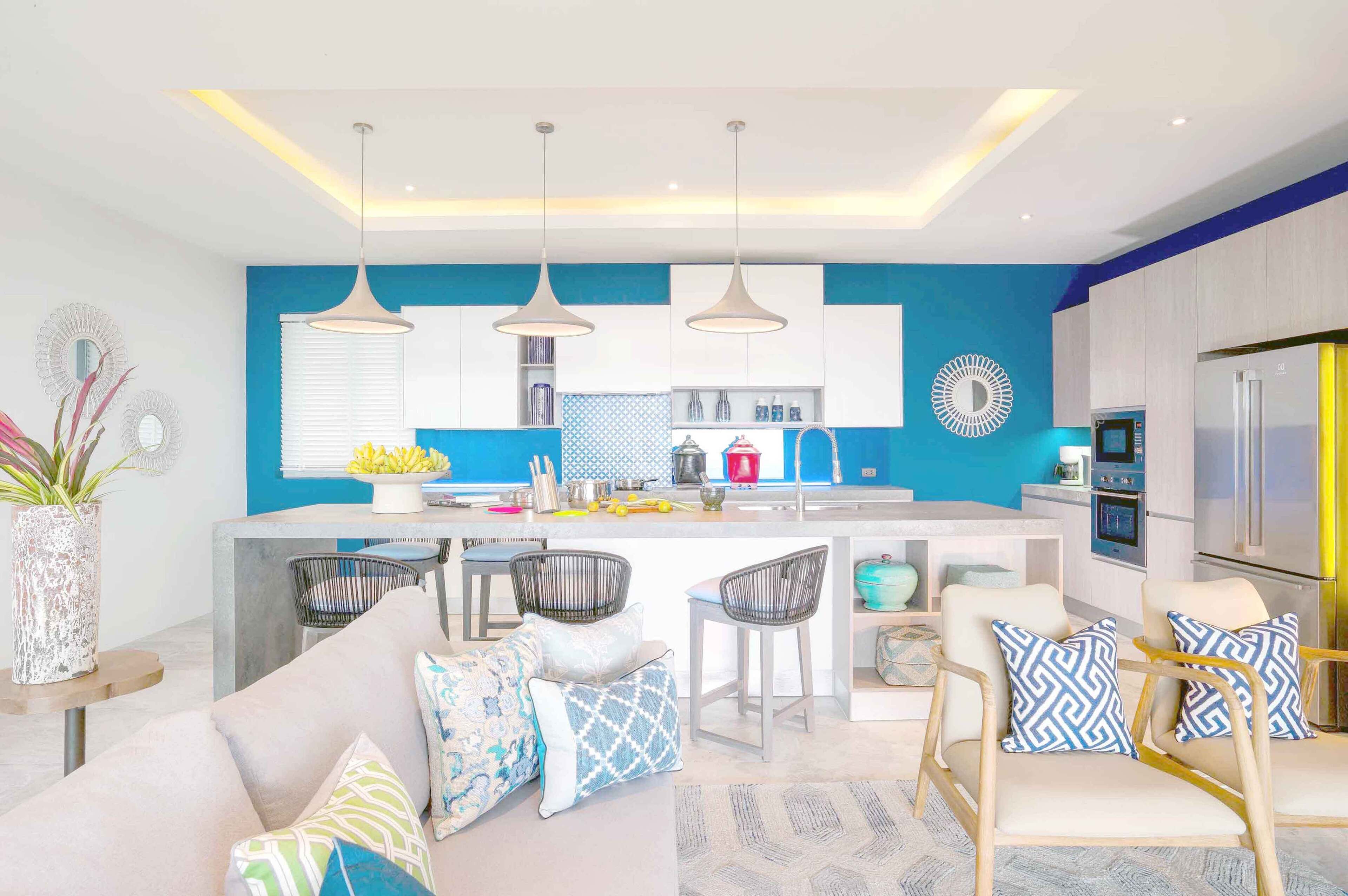 A modern kitchen with a central island, pendant lights, and a refrigerator.