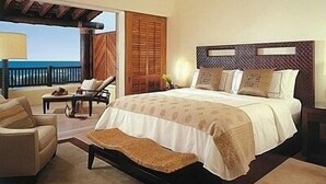 Un dormitorio con una cama grande, una silla, una mesita y vistas al exterior.