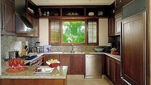 Una cocina con armarios de madera, una isla central, lavavajillas y una ventana con persianas.