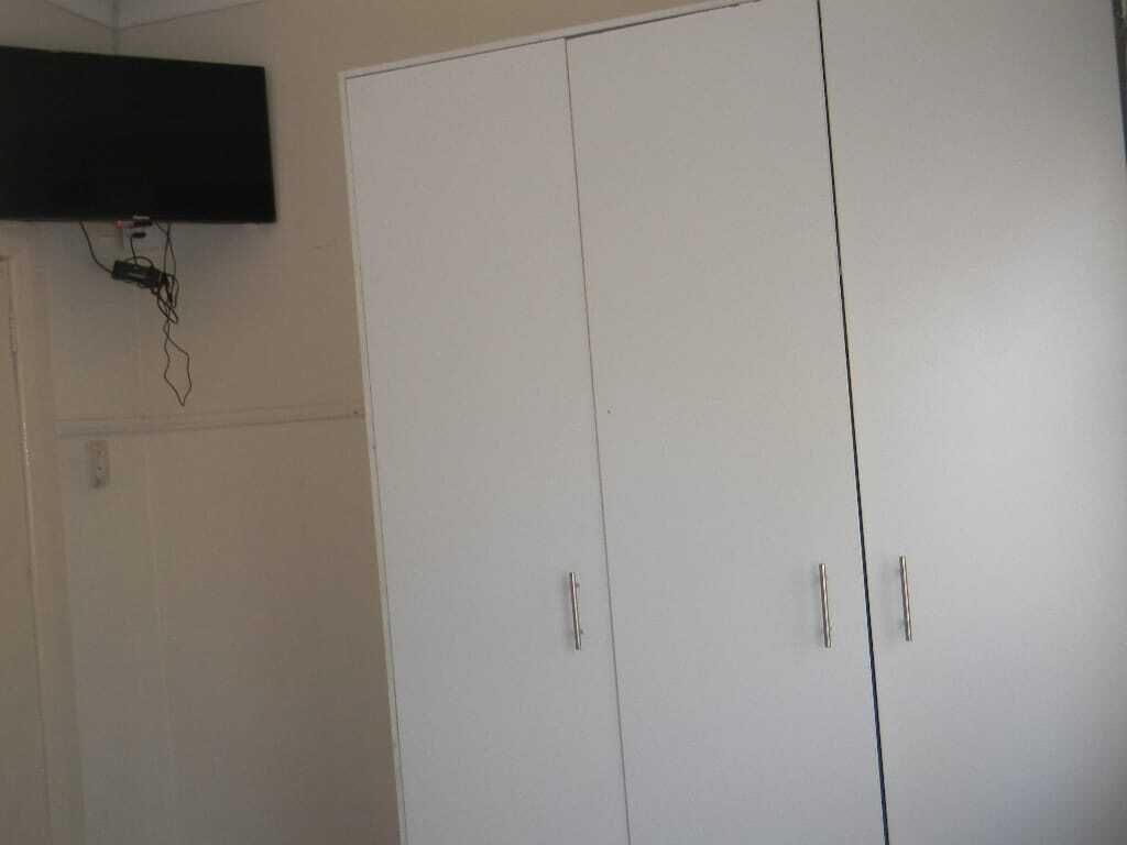 A white wardrobe with two doors and a small shelf above it.