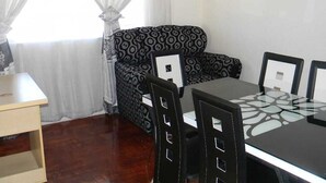 A dining area with a table and chairs, a patterned sofa, and a small table. - M2T Guest House (Cape Town)