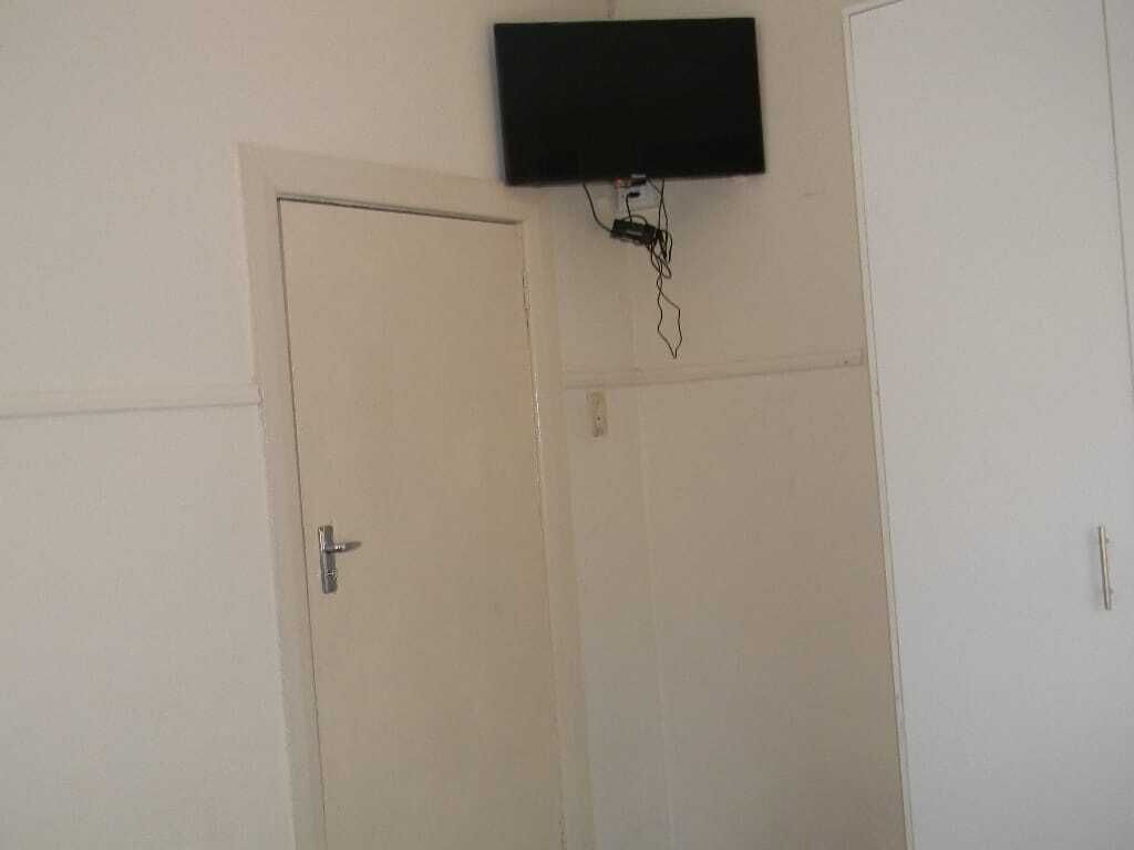 Una habitación con una puerta cerrada, un televisor montado y un enchufe en la pared.
