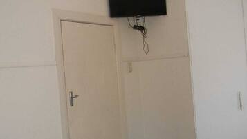 Een kamer met een gesloten deur, een bevestigde televisie en een wandcontactdoos.