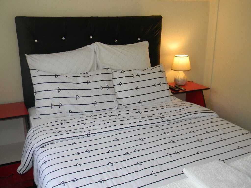 Ein Bett mit gestreifter Bettdecke und passenden Kissen, eine Nachttischlampe und ein Nachttisch.