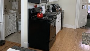 A compact kitchen with white cabinets, a black stove, and a microwave. - Brookside Cottage is a beautiful open concept doll house stay for two. (Berkeley Springs)