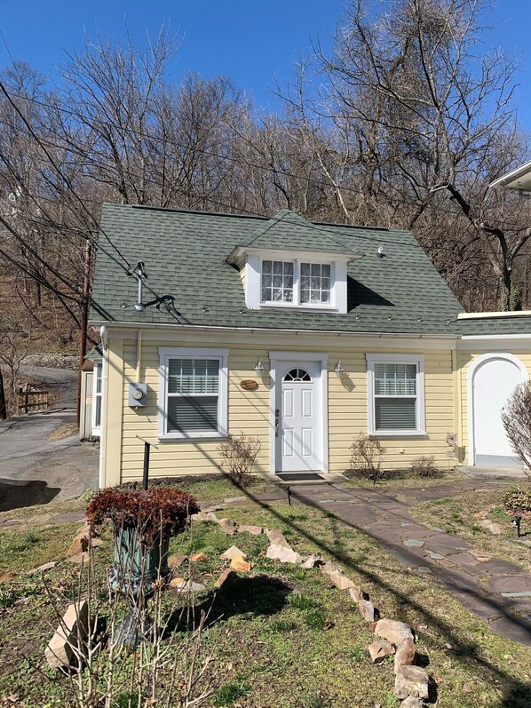 A single-story house with a green roof, a front door, and two windows. - Brookside Cottage is a beautiful open concept doll house stay for two. (Berkeley Springs)