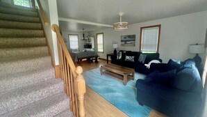 A spacious living room with a staircase, a blue sofa, a wooden coffee table, and a dining area with a table and chairs. - Perfect Family Escape! Walk to everything and relax. It’s all here for you  (York)