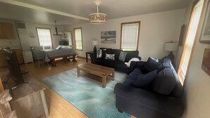 A living room with a sofa, a coffee table, a dining area with a table and chairs, and a kitchen area with appliances. - Perfect Family Escape! Walk to everything and relax. It’s all here for you  (York)