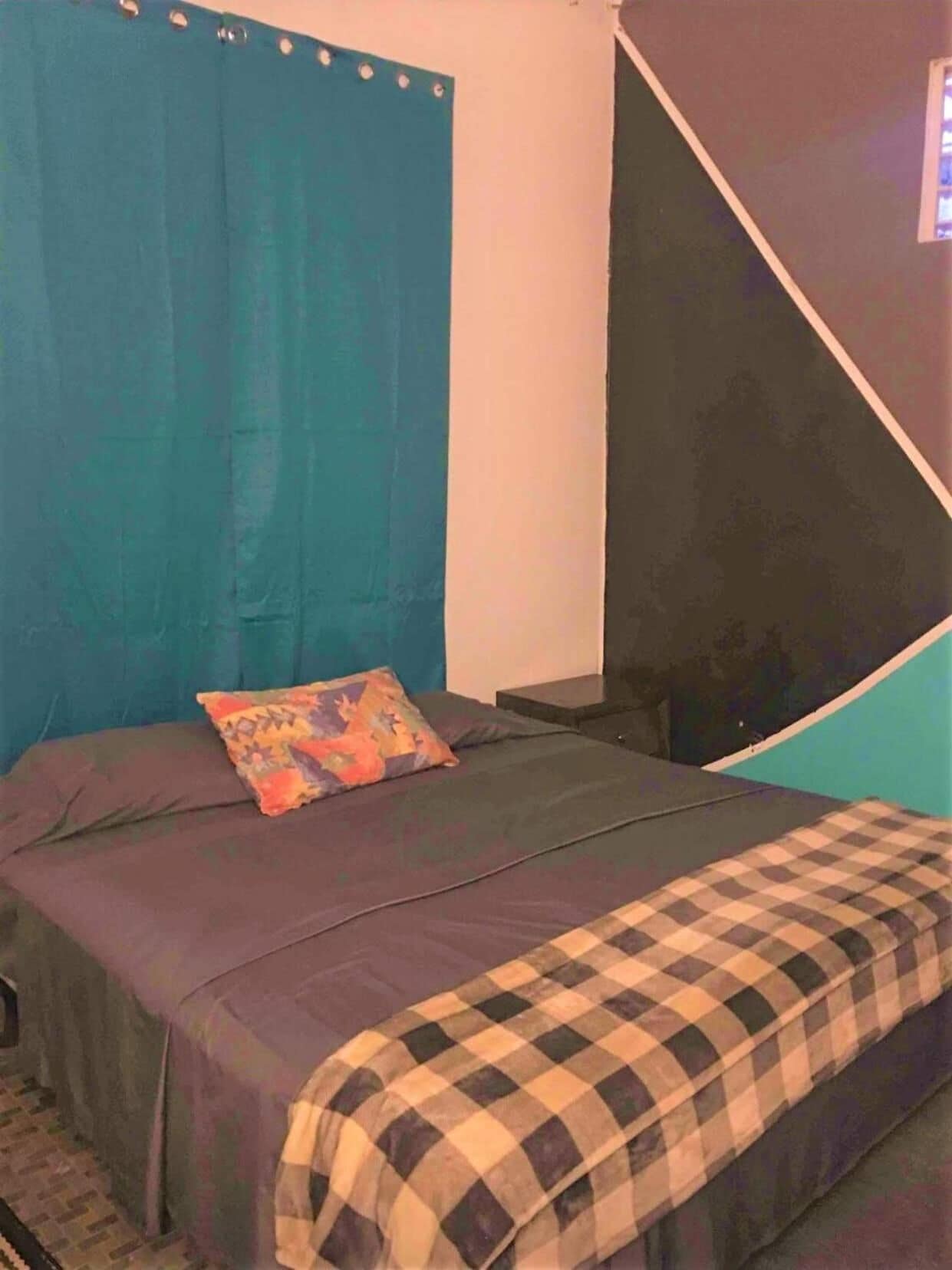 Um quarto com uma cama, um travesseiro e um cobertor xadrez.
