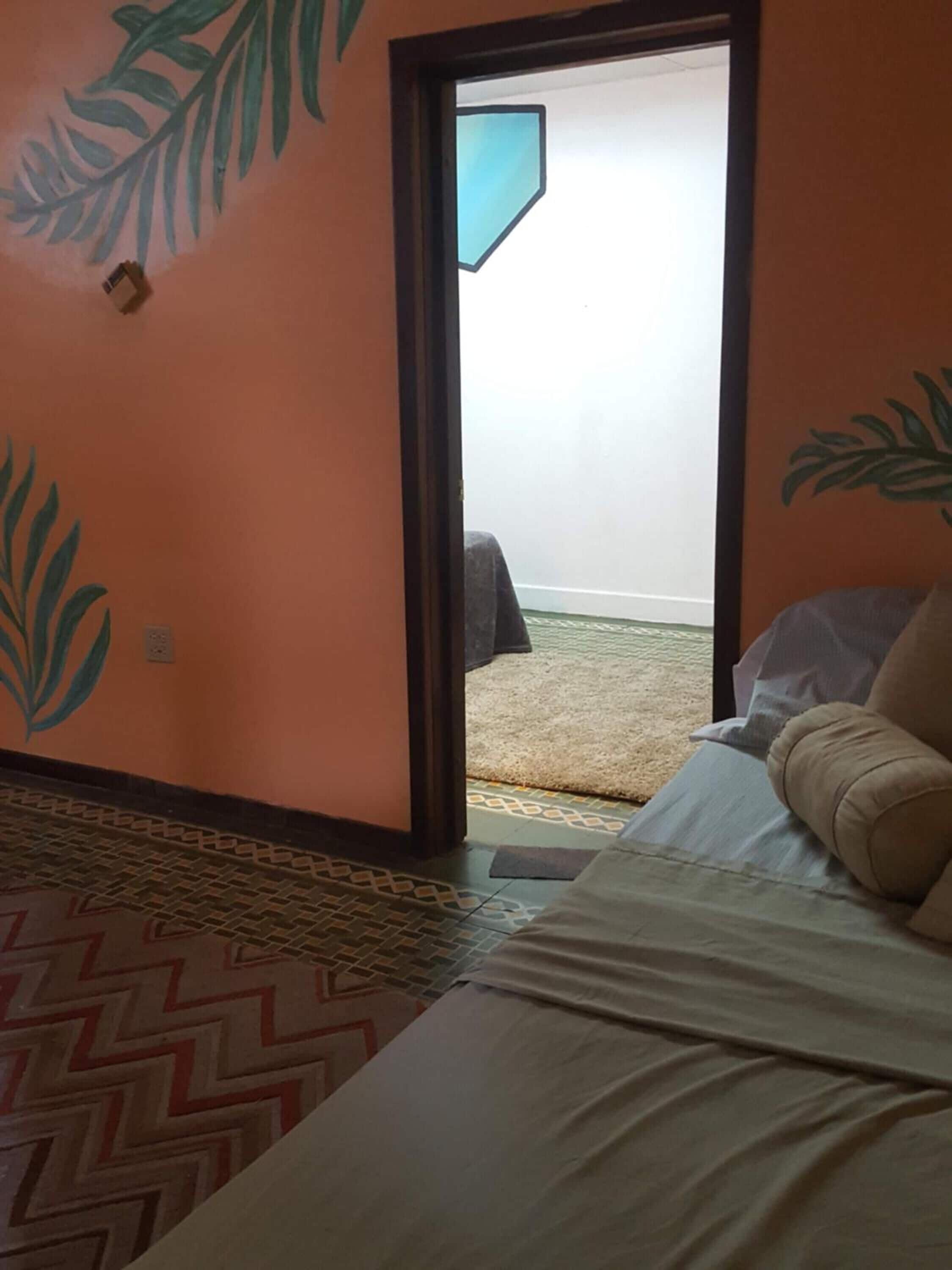 A room with a bed, a patterned floor, and a door leading to an outdoor area.