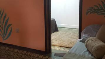 A room with a bed, a patterned floor, and a door leading to an outdoor area.