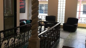 A spacious living area with a staircase, a ceiling fan, and a view of the outside. - Medusas Hostel (Aguadilla)