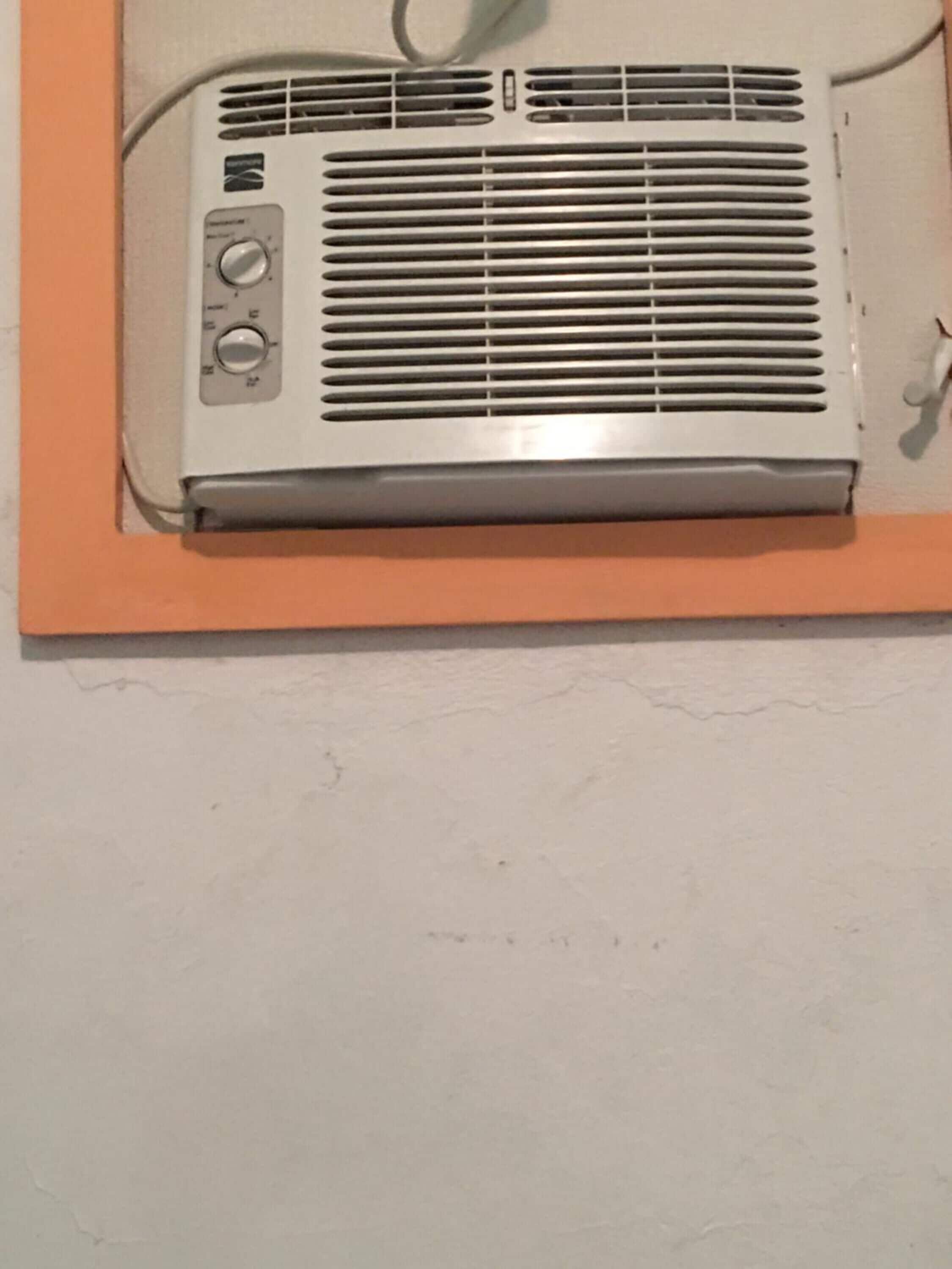 Un equipo de aire acondicionado instalado en la pared, con un panel de control y un cable de alimentación.