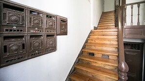 A wooden staircase with a wooden handrail and a white wall with vintage mailboxes. - Bhuiyan Family Host (Lisbon)