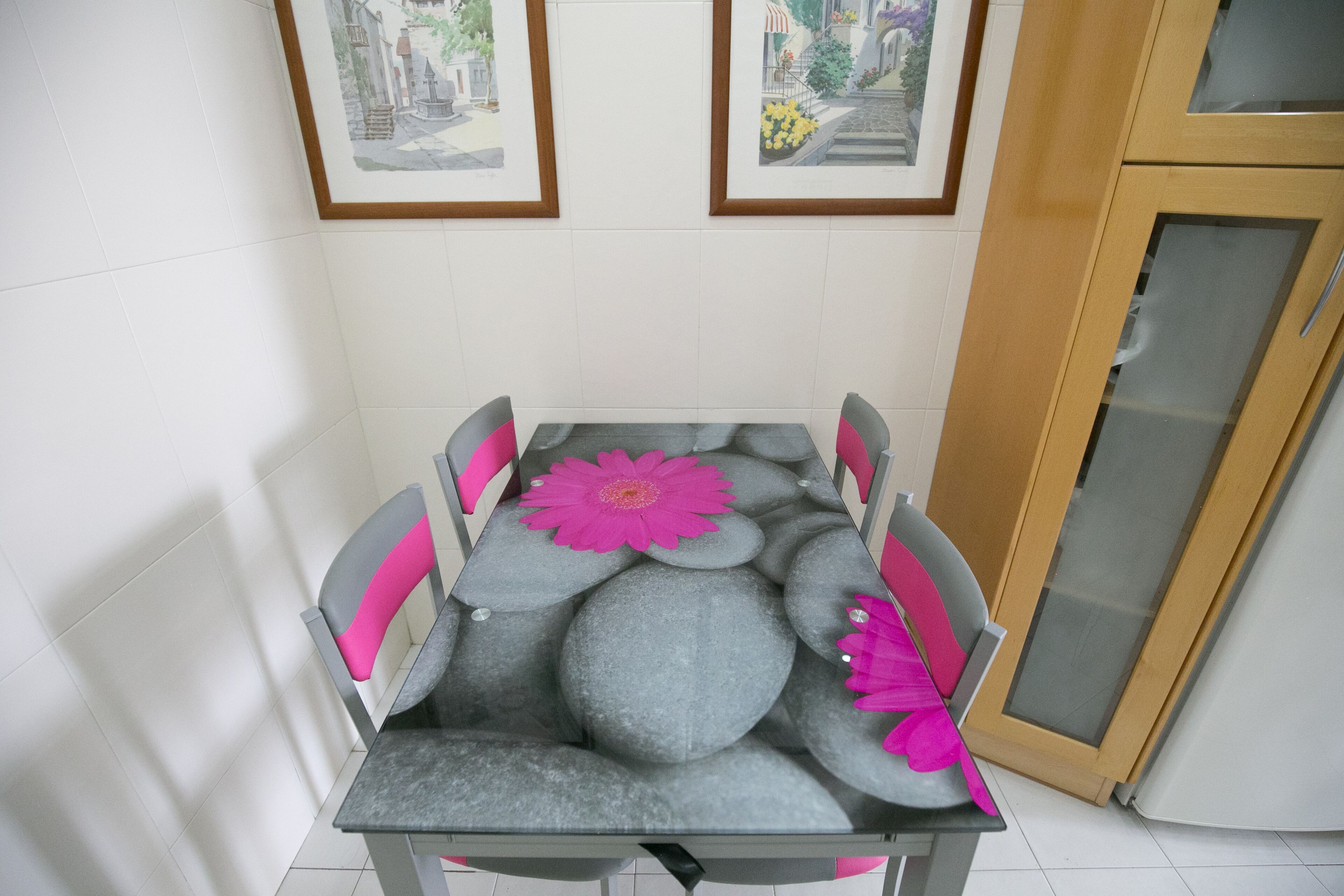Une table à manger avec un plateau en marbre gris, entourée de chaises dotées de coussins roses.