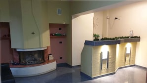 A modern interior with a fireplace, a curved seating area, and a built-in bar with illuminated lights. - Villa Luzzatti Hostel (Rome)
