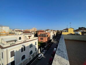 Vista de una calle con edificios, coches aparcados y cielo despejado.