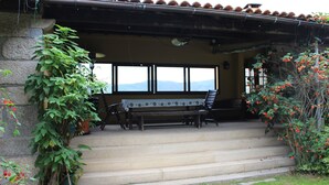 A stone building with a patio area featuring a bench and a table. - Quinta Do Pomarinho (Arouca)