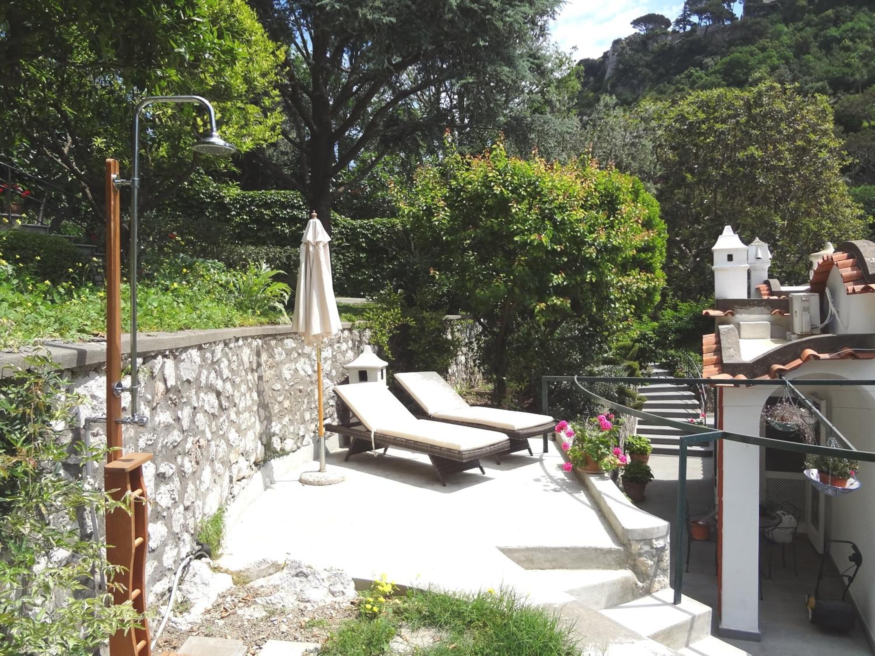 Una terraza en la azotea con sillones de descanso, un pérgola y un muro de piedra.