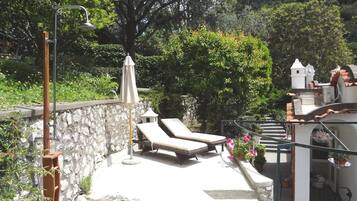 Una terraza en la azotea con sillones de descanso, un pérgola y un muro de piedra.