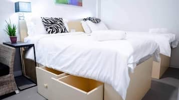 A modern bedroom with a bed, bedside tables, a lamp, and a wall-mounted artwork.
