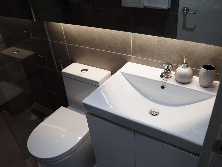 Une salle de bain moderne équipée de toilettes, d’un lavabo et d’une douche à parois en verre.
