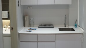 A modern bathroom with a white sink, a mirror, and a towel rack. - Radlett Residences (Tuguegarao)