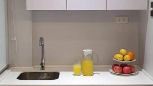 A small kitchen with a sink, faucet, and a fruit display. - Radlett Residences (Tuguegarao)